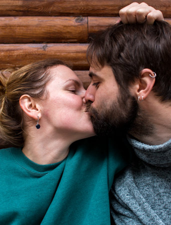 young couple kissing sitting near a wooden house in the forest. attitude and affection for each other. love.の写真素材