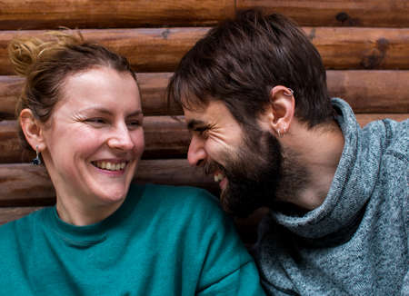 young couple spend time together sitting near a wooden house in the forest. attitude and affection for each other. love and tendernessの写真素材