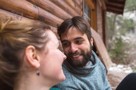young couple spend time together sitting near a wooden house in the forest. attitude and affection for each other. love and tendernessの写真素材