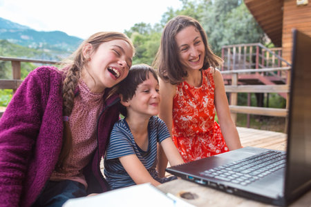 A woman and children look at a laptop screen, a boy and a girl communicate with relatives through video communication, communication at a distanceの写真素材