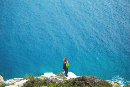 girl with a backpack stands on the shore and looks at the sea. travel alone.