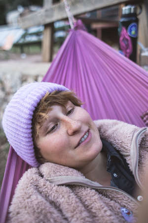 Red-haired girl with freckles lies in a hammock, portrait of a woman in a hat lying in a hammock, campingの写真素材