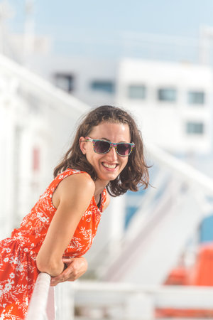 happy girl in a red sundress floats on the ship. summer ocean cruise. summer rest.の写真素材