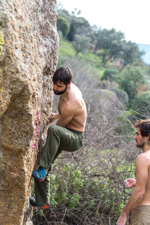 Two friends train to climb a large boulder, a man is engaged in rock climbing in nature, a man belays his partnerの写真素材