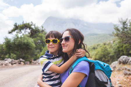 Portrait of a boy with mom on a background of mountains, a woman travels with a child, a child hugs...