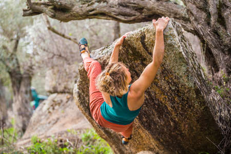 beautiful sports girl rock climber climbs the overhanging stone. bouldering in nature. sport climbing. fitness in nature.の写真素材