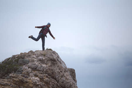 girl with a backpack stands on a mountain by the sea. the traveler looks at the sea, standing on the mountain. travel to turkey. freedom and happiness.の写真素材