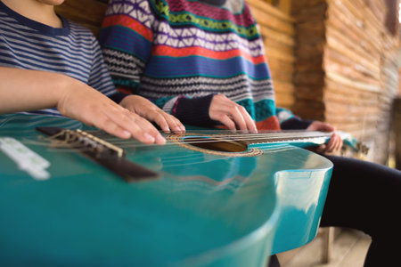 Children's and female hands on the strings of a guitar. learning to play a musical instrument. mom...