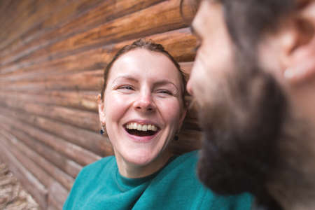 young couple spend time together sitting near a wooden house in the forest. attitude and affection for each other. love and tendernessの写真素材