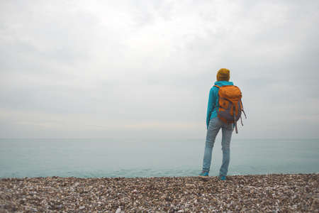girl with a backpack stands on the beach. travel alone. weekend walk.の写真素材