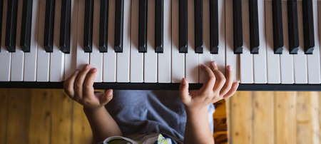 A child learns to play the piano. The boy makes keys. Music studio. Children's fingers on the black and white keys.の写真素材