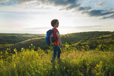 boy with a backpack on a hike. a hike with a child. summer vacation in nature.の写真素材
