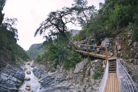A woman with a child go along a mountain river, a trip with children, a boy with a mother on a hike, a girl with a backpack.の写真素材