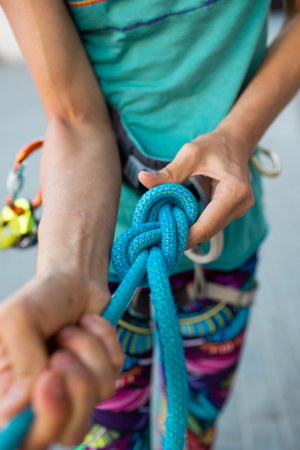 the climber ties the safety knot before climbing the route. training at the climbing wall. sports in...