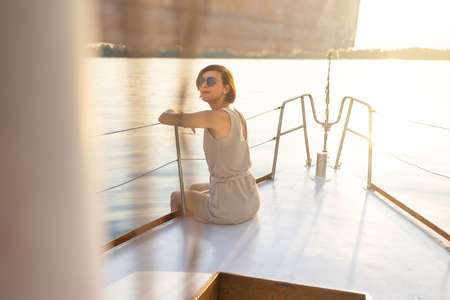 travel on a yacht. a young girl sits on the stern of a white yacht. privacy while traveling.の写真素材
