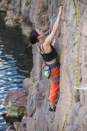 the girl is engaged in rock climbing by the water. a rock climber overcomes a difficult route....