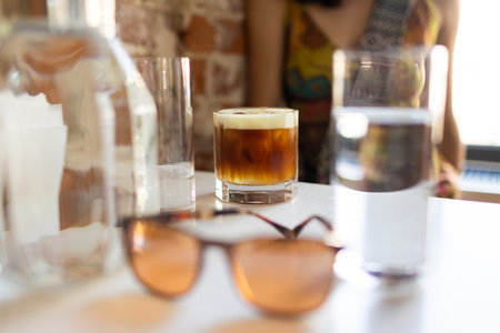 Sunglasses, glass of water and coffee on a table in a cafe, summer drinkの写真素材