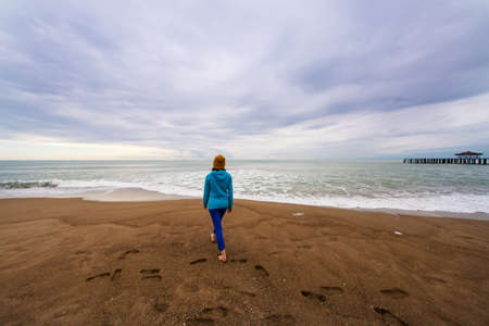 girl walks along the beach during a storm. traveling alone. weekend walk.の写真素材