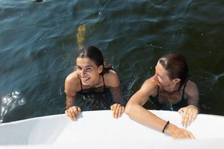 party on the yacht. girls swim in the water near the yacht. having fun and laughing at the holiday.