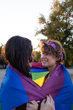 young lesbian couple hugs tenderly. rainbow flag on the street. equal rights for the lgbt community, intimacy and feelings for two girlsの写真素材