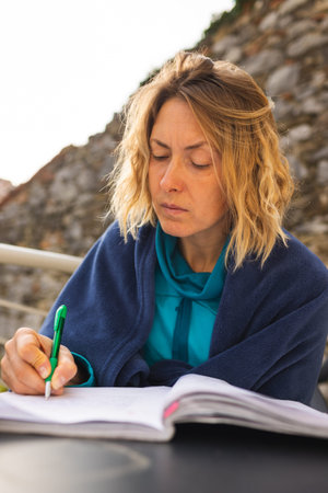 Woman works remotely, higher education for adults, woman writes in a notebook, freelancer does work...
