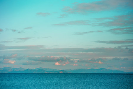 Beautiful seascape, the sun sets behind the mountains, rocky islands in the ocean, winter sea,...