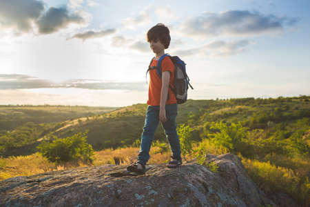 boy with a backpack on a hike. a hike with a child. summer vacation in nature.の写真素材