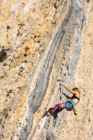 The girl climbs the rock. The climber trains on natural terrain. Extreme sport. Outdoor activities. A woman overcomes a difficult route rock climbing in Croatia area Kompanjの写真素材