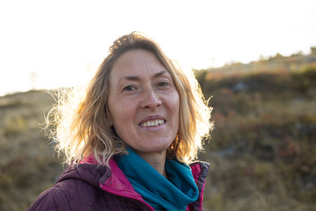 Portrait of smiling woman in sunbeams, blonde resting in nature, cheerful woman