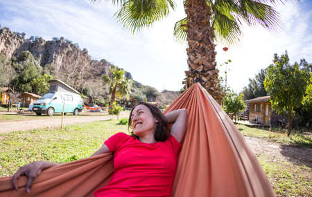 Portrait of a girl lying in a hammock, a woman resting in nature, traveling to beautiful places, camping.の写真素材