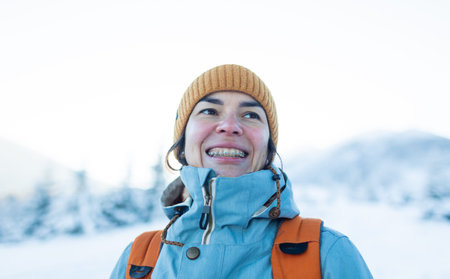 Smiling woman with braces on her teeth, portrait of a girl against the backdrop of winter mountains...