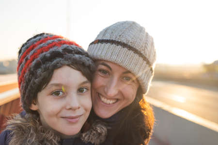 mom and son hug and look at each other. portrait of happy mother and son. winter walk along the street.の写真素材