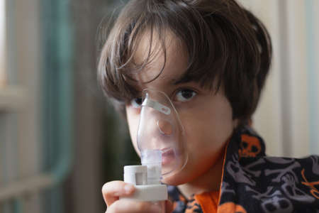 the child does inhalation, the boy inhales the medicine through the mask, nebulizer mask, treatment of the diseaseの写真素材