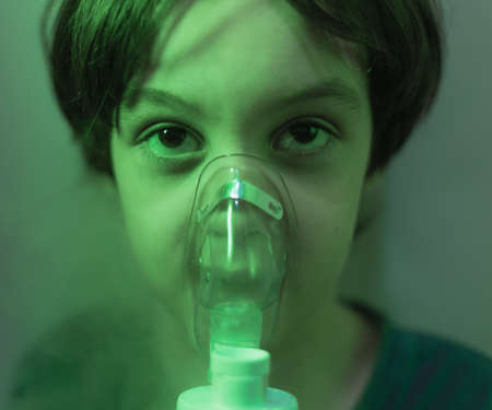 the child does inhalation, the boy inhales the medicine through the mask, nebulizer mask, treatment of the diseaseの写真素材