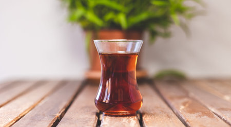 Glass of turkish tea on wooden table, potted plant and turkish traditional tea
