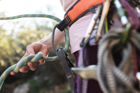 A rock climber prepares equipment for climbing, a woman holds a rope in her hands, a climber ties a...