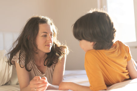Mother and son, the boy with his mom lies on the bed, the child spends the morning with his mother,...