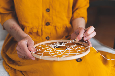 Woman making a dream catcher from threads, home decor making, handmade amuletの写真素材