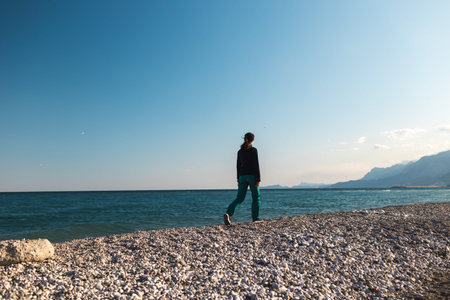 A girl walks along the beach alone, a woman looks at the sea, a brunette against the background of...