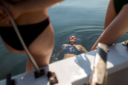the girl lies on the water and enjoys it. Party on the yacht. rest and time with friendsの写真素材
