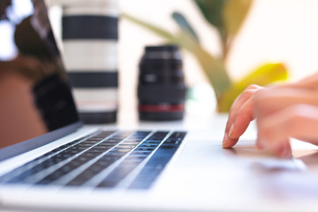 Photographer's workplace, laptop and camera lenses on a white table, photographer concept with...