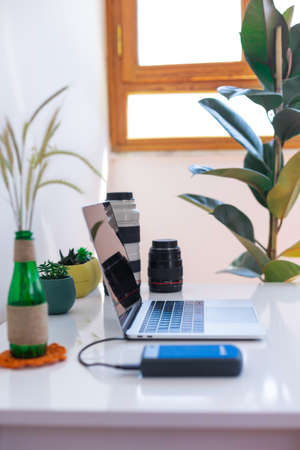 Photographer's workplace, laptop and camera lenses on a white table, photographer concept with digital camera, external harddisk, notebook and camera accessory on white background with copy spaceの写真素材