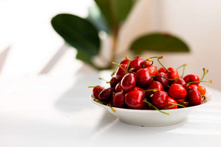 A bowl of sweet cherries on a white table, sweet berry, summer harvestの写真素材