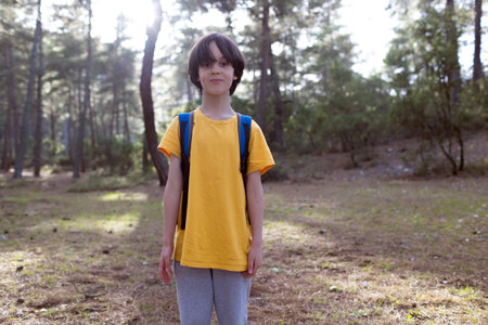 A boy with a backpack in the forest, a child walks in nature, a portrait of a child