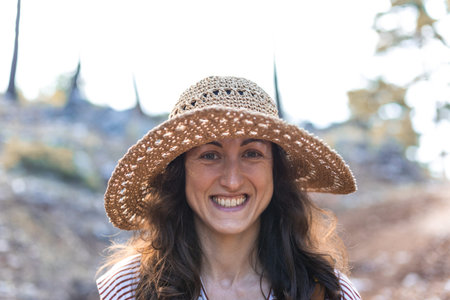Portrait of a woman with a backpack and a straw hat in the forest, a smiling girl on a hike, summer...