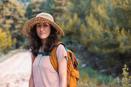 A woman with a backpack on a hike in the mountains, a girl in a hat walks along a forest path, a...