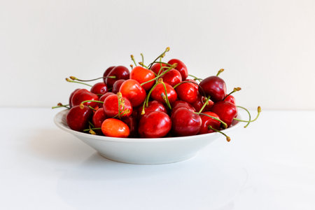 A bowl of sweet cherries on a white table, sweet berry, summer harvest