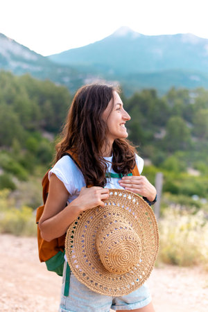 a young and beautiful girl with a backpack looks around and smiles. travel and freedom concept.