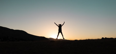 girl jumping at sunset in the mountains. skyrunning. a young girl walks along a mountain range at...