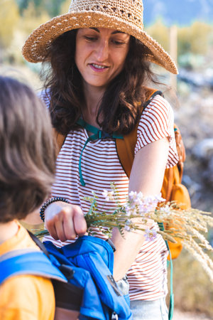 mother and son on a hike. mother takes things out of the child's backpack. the boy travels with his mother along a mountain path and forests. summer holiday.の写真素材